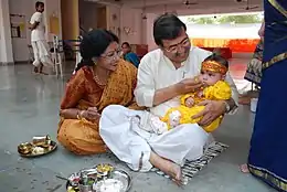 Image 17Samskaras are, in one context, the diverse rites of passage of a human being from conception to cremation, signifying milestones in an individual's journey of life in Hinduism. Above is annaprashana samskara celebrating a baby's first taste of solid food. (from Samskara (rite of passage))